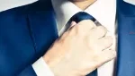 Homem fazendo o nó da gravata, disponível na Cristina Carneiro Aluguel de Roupas.